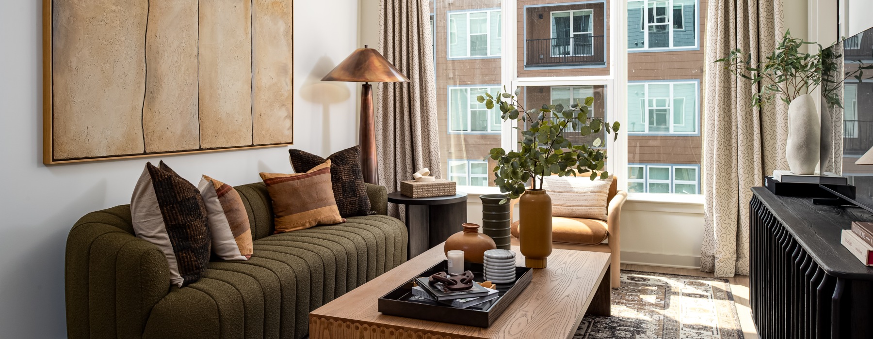living room with couch coffee table and tv stand with tv with large windows 